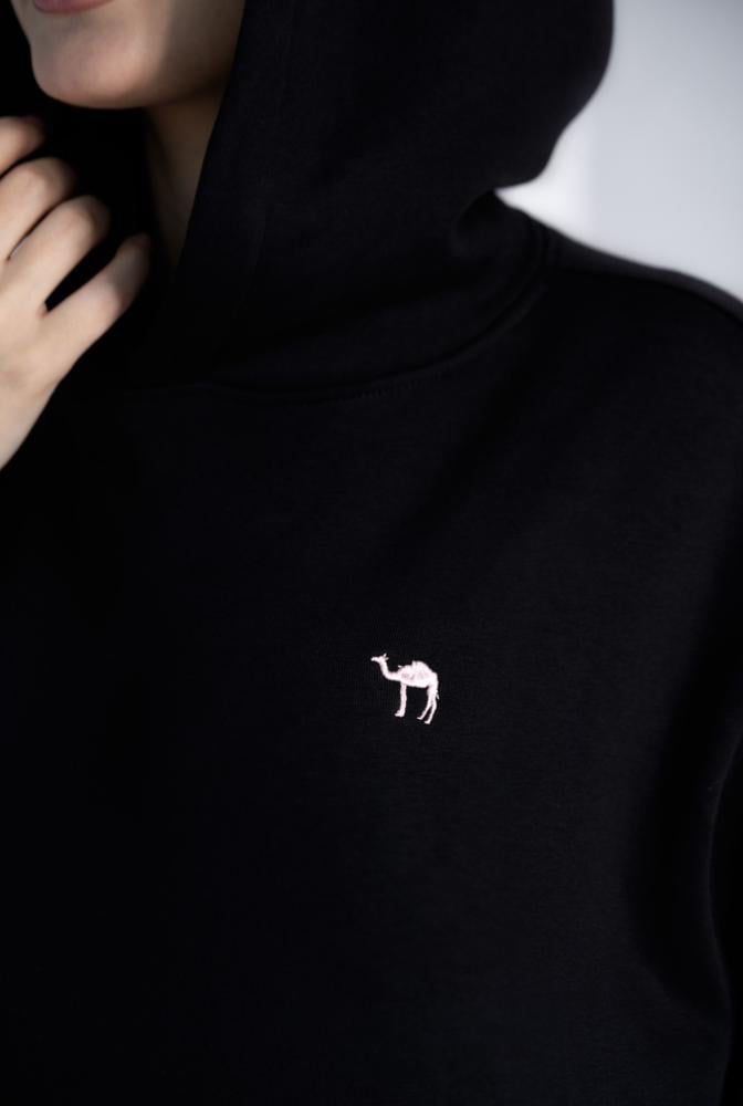 Black hoodie with a white embroidered camel logo on a neutral background