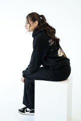 Person wearing a black tracksuit with visible branding on a white background